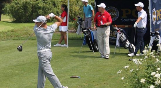 Player swinging their golf club while others watch