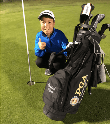 Boy with his thumb up next to a golf bag